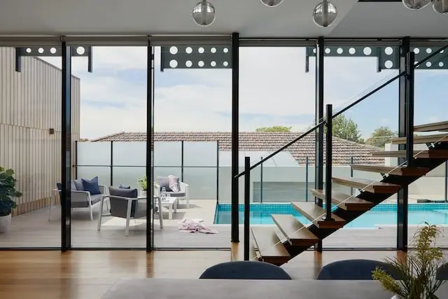 Grandes baies vitrées et escalier ouvrant sur une piscine