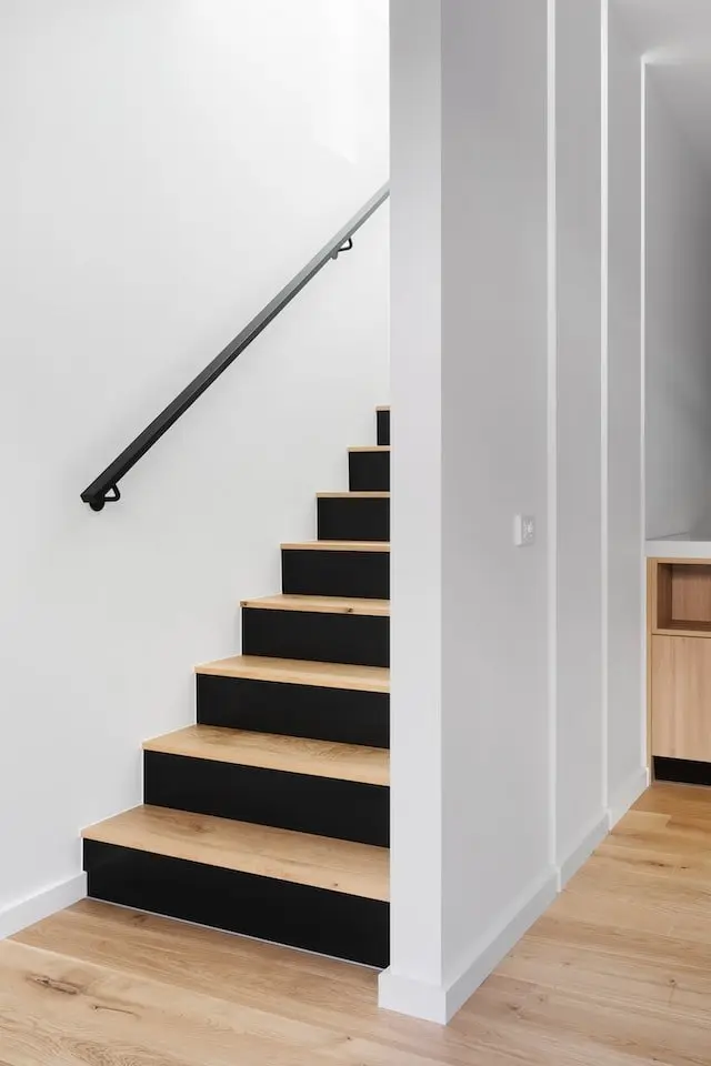 Escalier aux marches en bois et contremarches noires avec main courante murale